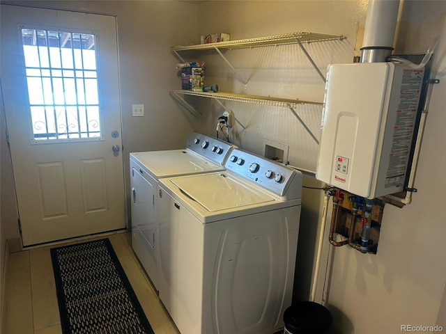 laundry room featuring tankless water heater, washing machine and dryer, and light tile patterned floors