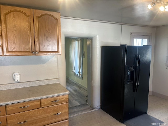 kitchen with black refrigerator with ice dispenser and light wood-type flooring