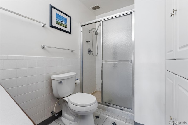 bathroom with tile patterned flooring, an enclosed shower, tile walls, and toilet