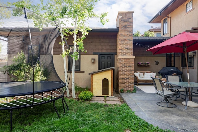 1143 S Saint Paul St, Denver, CO 80210 - rear view of house with a chimney, stucco siding, a trampoline, a patio area, and an outdoor hangout area