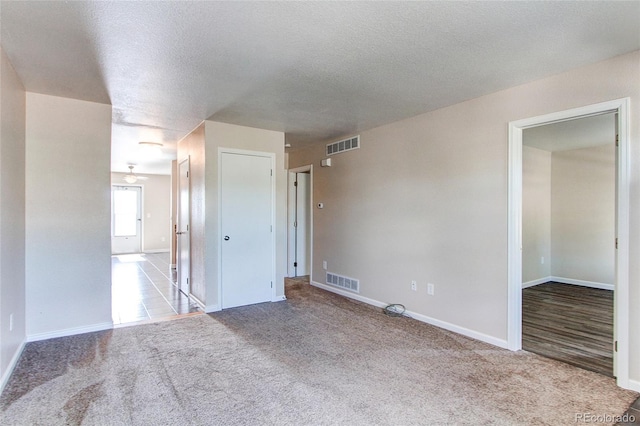 empty room with carpet flooring, visible vents, baseboards, and a ceiling fan