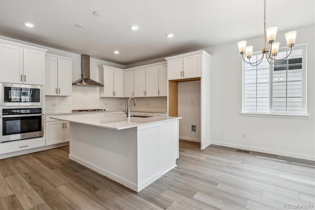 39161 Anthony St, Elizabeth, CO 80107 - kitchen featuring appliances with stainless steel finishes, wall chimney range hood, a sink, light wood-type flooring, and light countertops