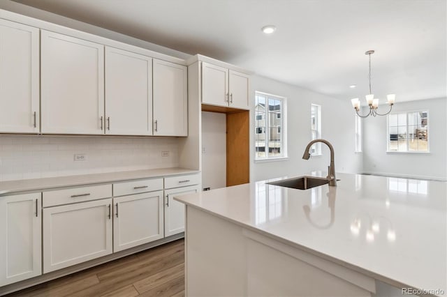 39161 Anthony St, Elizabeth, CO 80107 - kitchen with a sink, a chandelier, decorative backsplash, light wood-style floors, and light countertops