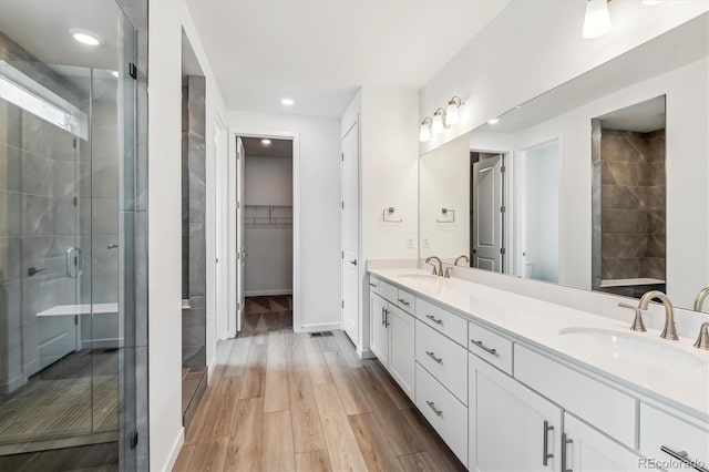 39161 Anthony St, Elizabeth, CO 80107 - bathroom with a shower stall, double vanity, wood finished floors, a walk in closet, and recessed lighting
