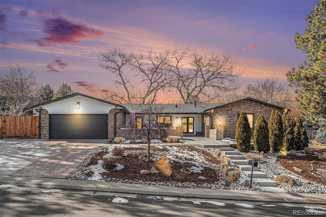 view of front of property with brick siding, concrete driveway, an attached garage, and fence