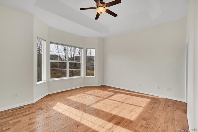 spare room with light hardwood / wood-style flooring, ceiling fan, and a tray ceiling