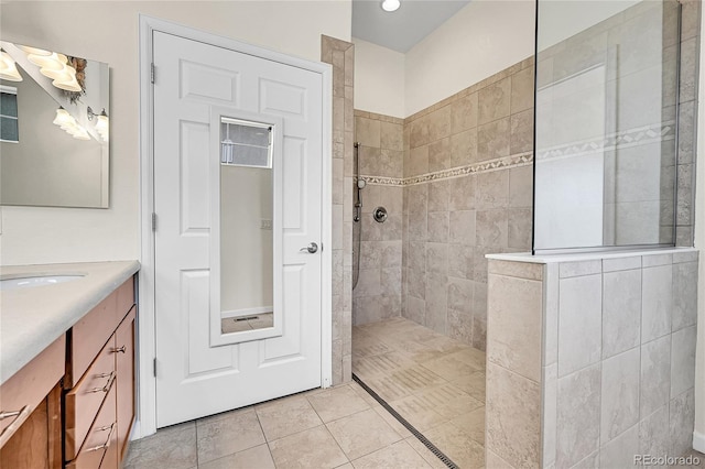 bathroom with tiled shower, vanity, and tile patterned flooring