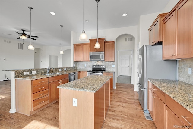 kitchen with pendant lighting, a center island, kitchen peninsula, and appliances with stainless steel finishes