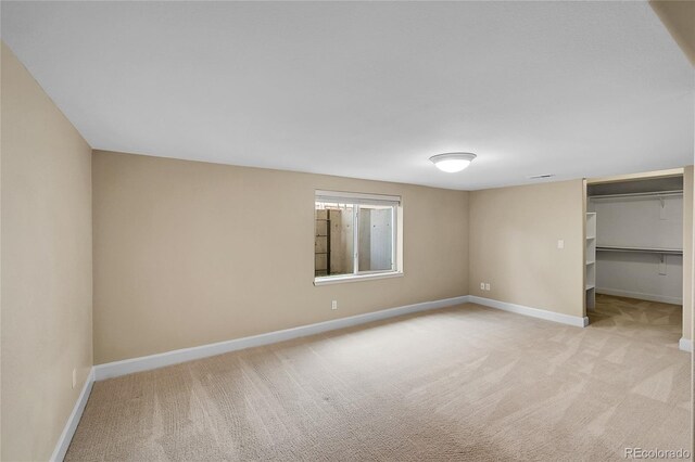 unfurnished bedroom featuring a walk in closet and light carpet