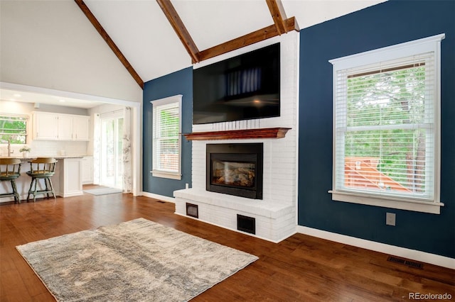 969 Pulpit Rock Ct, Colorado Springs, CO 80918 - living room featuring a brick fireplace, beam ceiling, high vaulted ceiling, dark wood-style flooring, and baseboards