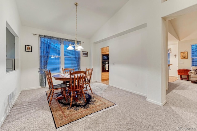 dining area with baseboards, high vaulted ceiling, a chandelier, and light carpet