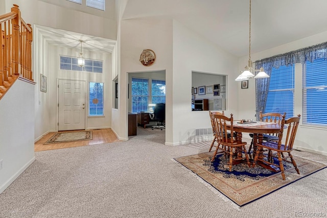 carpeted dining room featuring baseboards, stairs, and high vaulted ceiling