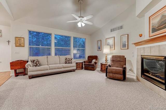 carpeted living room featuring visible vents, baseboards, a tiled fireplace, a ceiling fan, and vaulted ceiling