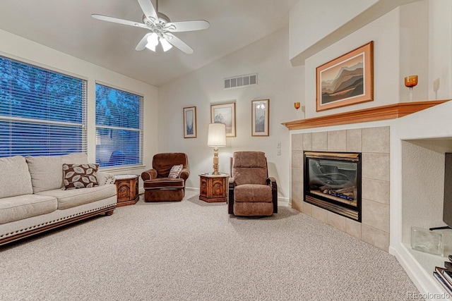 living area with a ceiling fan, visible vents, a fireplace, lofted ceiling, and carpet