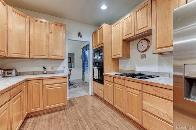 kitchen with light brown cabinetry, light wood-style floors, recessed lighting, tile countertops, and black appliances