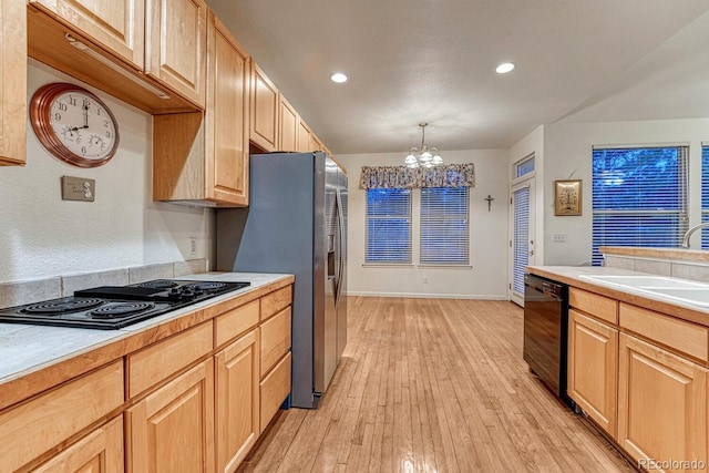 kitchen with a sink, light countertops, an inviting chandelier, and black appliances