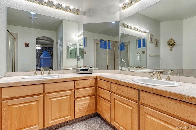 full bathroom featuring ceiling fan, visible vents, a sink, and a stall shower