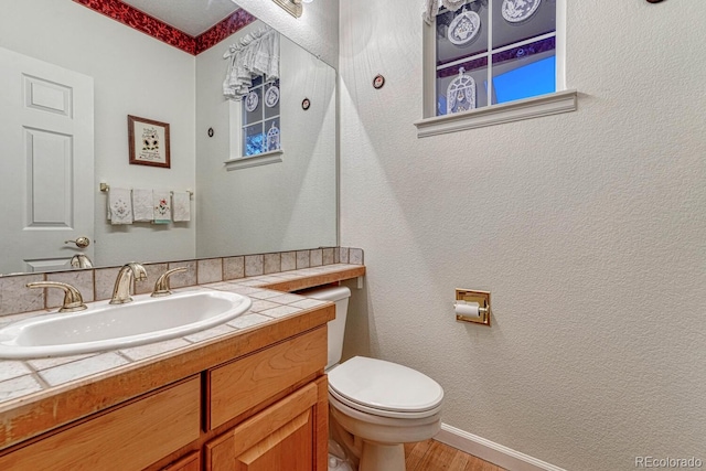 bathroom with vanity, baseboards, wood finished floors, and toilet