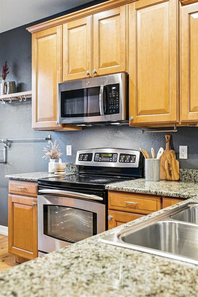 2319 Decatur St, Denver, CO 80211 - kitchen with stainless steel appliances, wood finished floors, and light stone counters
