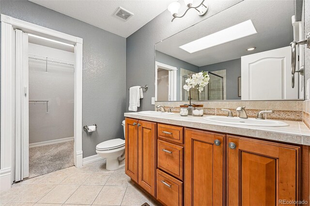 2319 Decatur St, Denver, CO 80211 - full bath with double vanity, a shower stall, a skylight, a walk in closet, and tile patterned floors