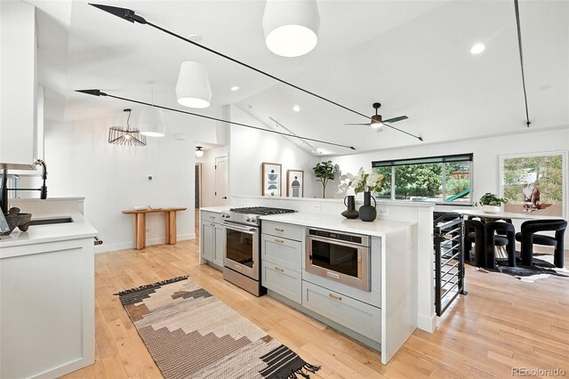1920 S Niagara St, Denver, CO 80224 - kitchen with stainless steel stove, light countertops, a ceiling fan, light wood-style floors, and vaulted ceiling
