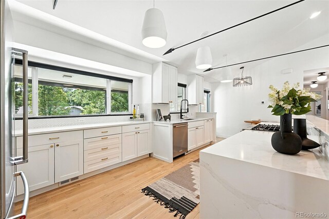 1920 S Niagara St, Denver, CO 80224 - kitchen featuring dishwasher, white cabinetry, light wood-type flooring, decorative light fixtures, and a chandelier