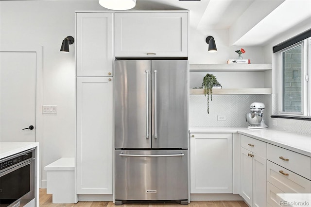 1920 S Niagara St, Denver, CO 80224 - kitchen featuring stainless steel appliances, tasteful backsplash, white cabinets, light wood-style flooring, and light countertops