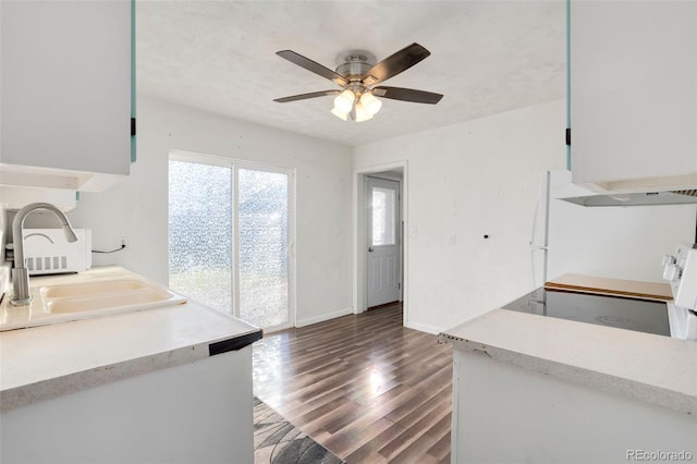 kitchen featuring stove, dark wood-type flooring, exhaust hood, sink, and ceiling fan