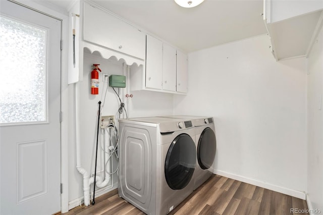 clothes washing area featuring separate washer and dryer, dark hardwood / wood-style flooring, and cabinets