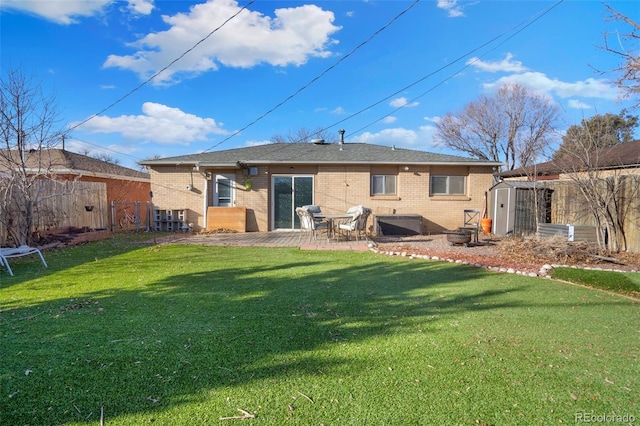 back of property with a lawn, a patio area, and a shed