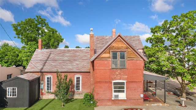 805 5th St, Fort Lupton, CO 80621 - rear view of house featuring a patio area, brick siding, a yard, a chimney, and a storage shed