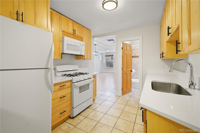 kitchen with light tile patterned flooring, white appliances, sink, and light brown cabinets