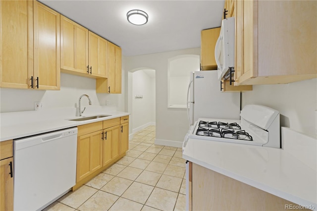 kitchen with light tile patterned flooring, white appliances, light brown cabinetry, and sink