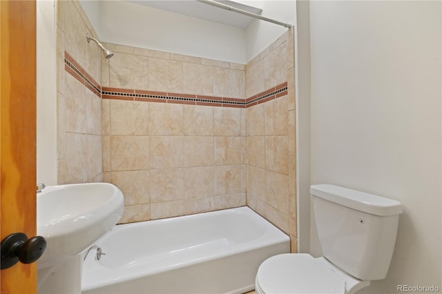 bathroom featuring tiled shower / bath combo and toilet