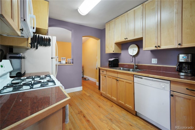 kitchen featuring white dishwasher, gas range oven, sink, and light brown cabinetry