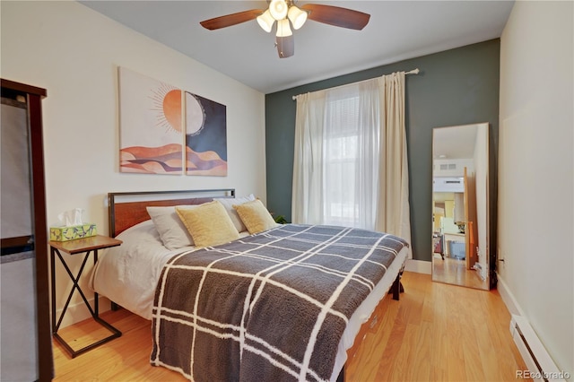 bedroom with ceiling fan, hardwood / wood-style floors, and a baseboard heating unit