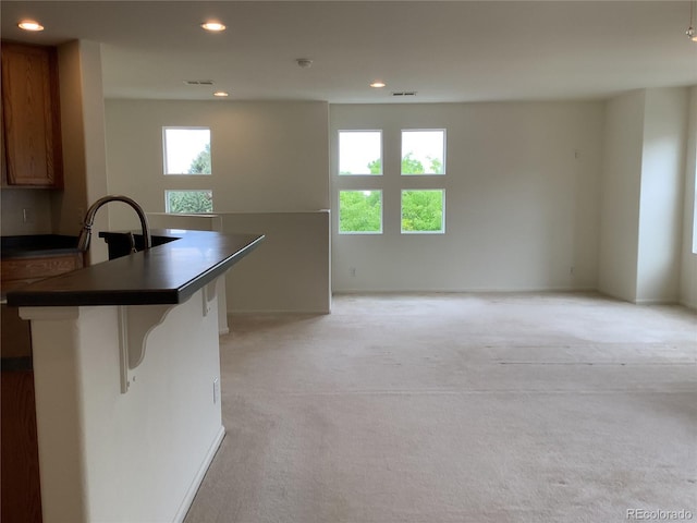 11947 Riverstone Cir Unit 7F, Henderson, CO 80640 - kitchen featuring light colored carpet, a kitchen bar, recessed lighting, dark countertops, and open floor plan