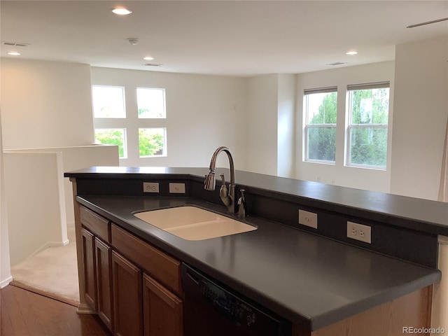 11947 Riverstone Cir Unit 7F, Henderson, CO 80640 - kitchen featuring a sink, dark countertops, dishwasher, a kitchen island with sink, and dark wood-style floors
