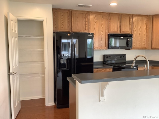 11947 Riverstone Cir Unit 7F, Henderson, CO 80640 - kitchen featuring black appliances, dark countertops, recessed lighting, brown cabinets, and a kitchen bar