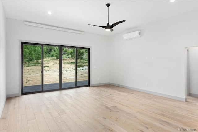 spare room with a wall mounted air conditioner, light hardwood / wood-style floors, and ceiling fan