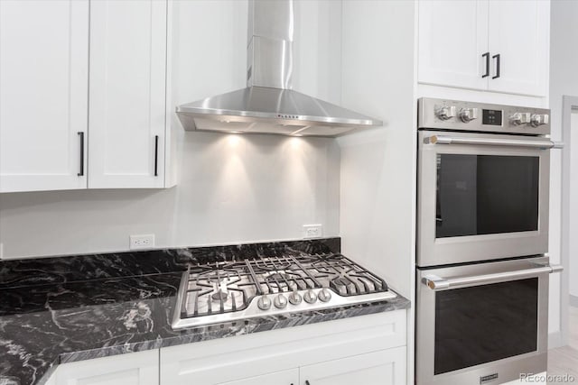 kitchen with white cabinetry, appliances with stainless steel finishes, and wall chimney range hood