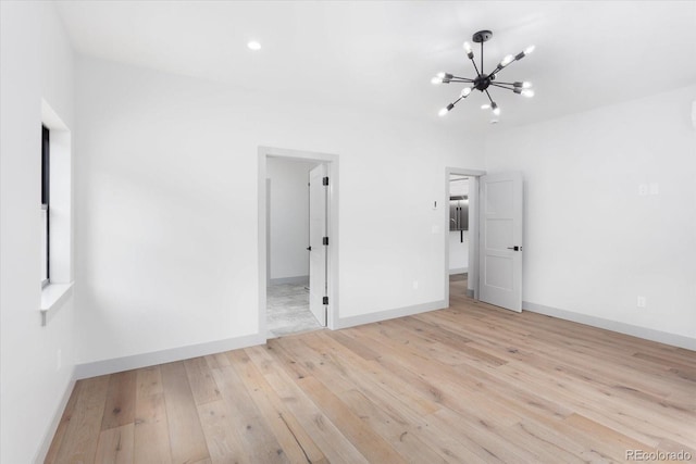 unfurnished bedroom featuring a chandelier and light hardwood / wood-style flooring