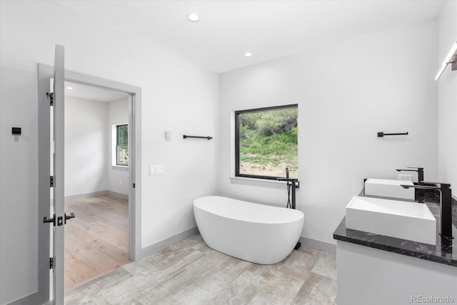 bathroom featuring vanity, a tub to relax in, and hardwood / wood-style flooring