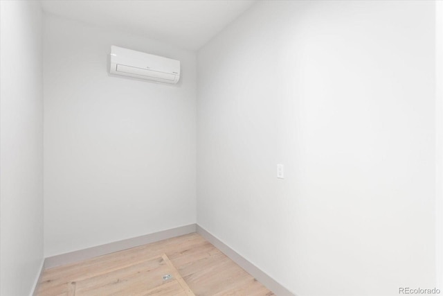 spare room with a wall mounted air conditioner and light hardwood / wood-style floors