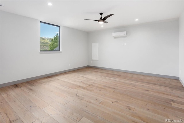 unfurnished room featuring ceiling fan, a wall mounted air conditioner, and light hardwood / wood-style flooring