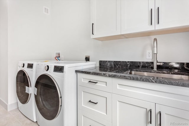 washroom with sink, light tile patterned floors, washing machine and dryer, and cabinets