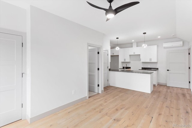 kitchen featuring white cabinetry, a wall mounted AC, hanging light fixtures, ceiling fan, and light hardwood / wood-style floors