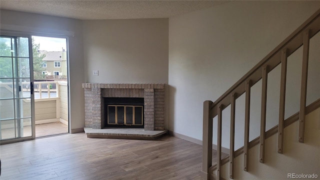 1818 S Quebec Way Unit 5-7, Denver, CO 80231 - unfurnished living room featuring wood finished floors, stairway, a textured ceiling, and a fireplace