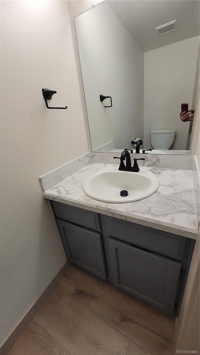 1818 S Quebec Way Unit 5-7, Denver, CO 80231 - half bath featuring vanity, wood finished floors, toilet, and baseboards