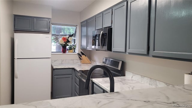1818 S Quebec Way Unit 5-7, Denver, CO 80231 - kitchen with freestanding refrigerator, stainless steel microwave, gray cabinets, range with electric cooktop, and light stone countertops